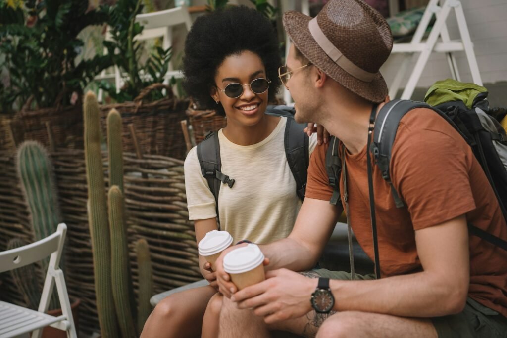 stylish interracial couple sitting with paper cups of coffee